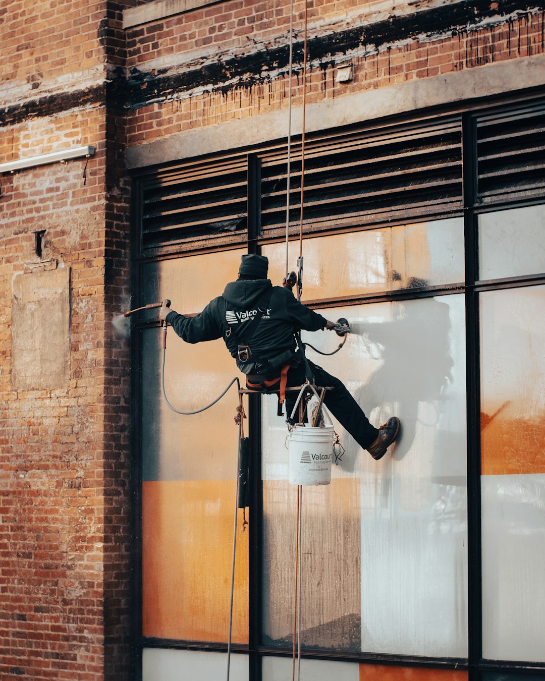 a-man-hanging-from-a-rope-on-top-of-a-building-jxivglsbp-k